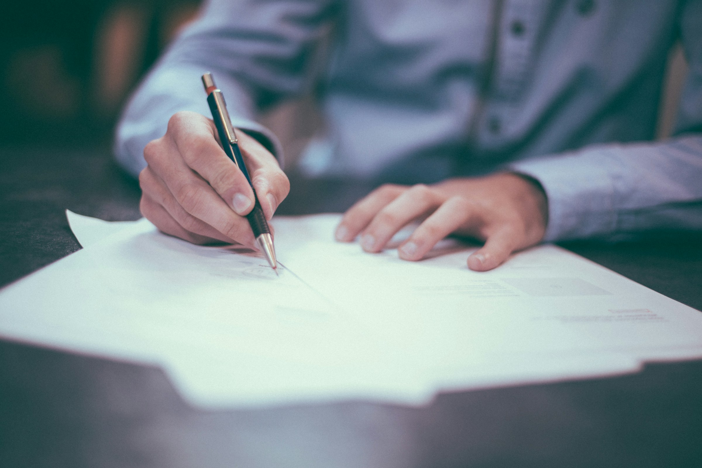 Close-up of a hand signing a financial agreement, representing structured finance